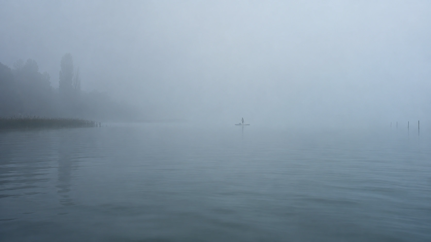 Sűrű köd a Balatonon, a vízen egy magányos SUP-ossal, alig látható partvonallal.